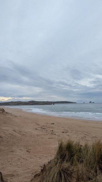 A wide sandy beach with breaking waves on a cloudy day at Liencres. — Liencres (Cantábria), Piélagos, Cantabria, Spain
