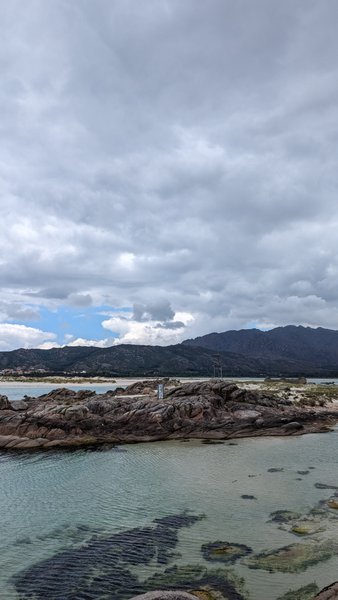 A view of the rocky shoreline and clear water at Playa de Carnota under a cloudy sky. — Praia de Carnota (Carnota), Carnota, Galicia, Spain