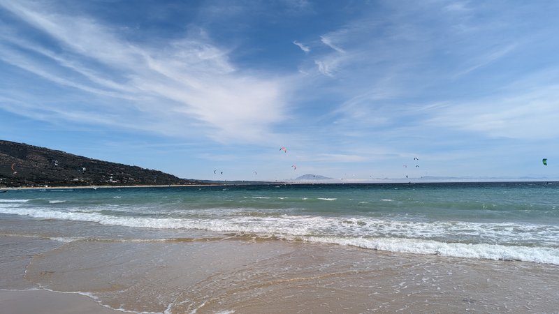 A wide view of Punta Paloma beach with several kites flying over the water.