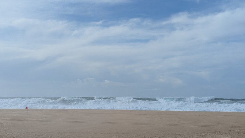 A view of the breaking surf and wide sandy beach at Praia do Norte. — Praia do Norte (North Beach), Nazaré, Portugal