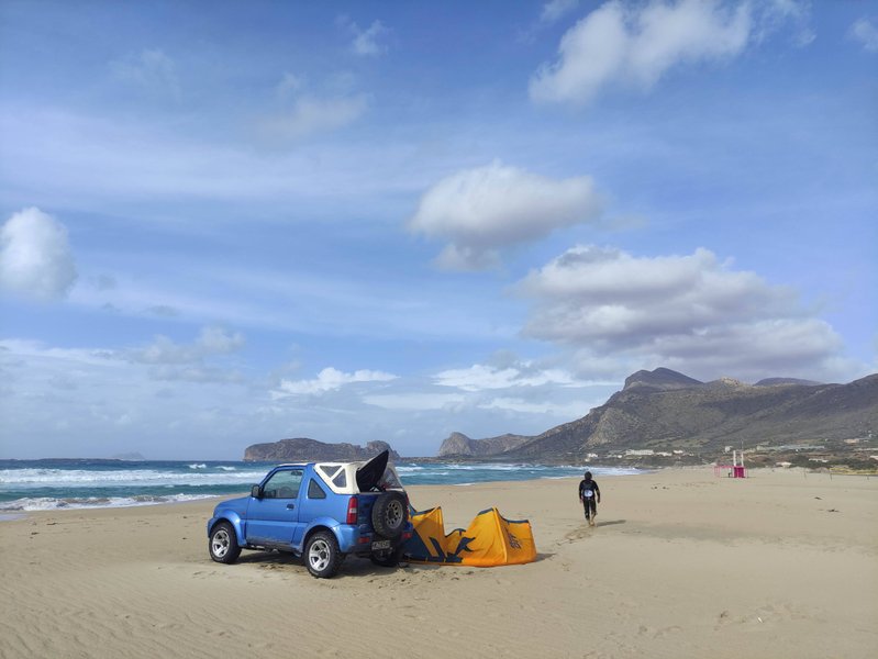 A vehicle parked on the sandy beach at Falasarna with the ocean and mountains in the background. — Falasarna-Riff (Platanos), Platanos, Region of Crete, Greece