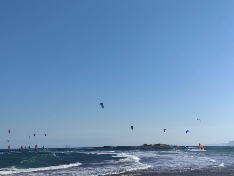 Kitesurfers and windsurfers on the water at Nissakia Loutsa under a clear sky.