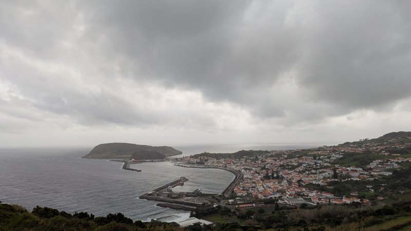 A panoramic view of a coastal town, bay, and island under a cloudy sky. — Praia do Almoxarife (Almoxarife), Praia do Almoxarife, Portugal