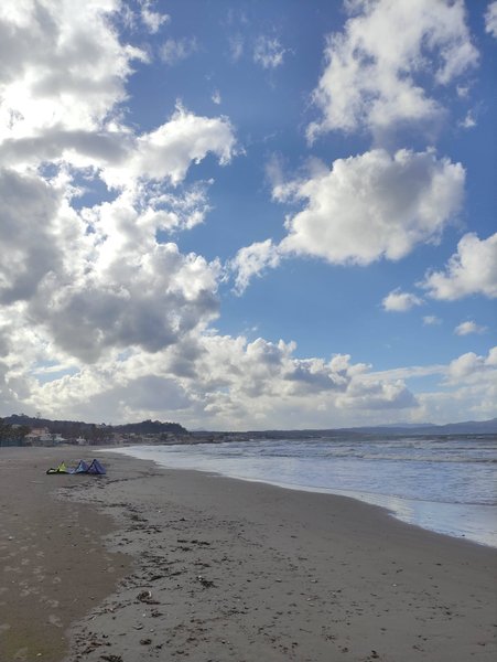 A wide view of the beach and water at Agia Marina Platanias with kites on the sand.