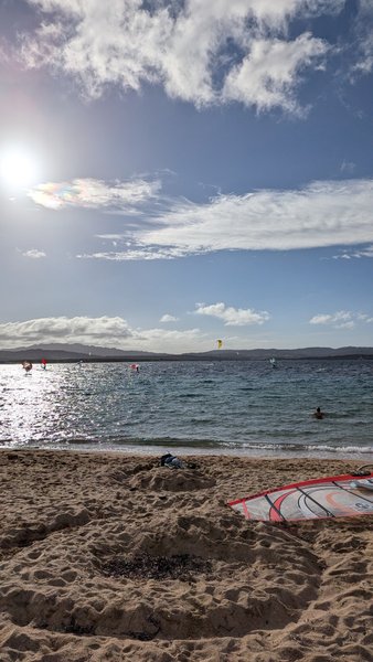 A sunny day at Isola dei Gabbiani featuring the beach and several windsurfers on the water. — Isola Gabbiani (Palau Coast), Lu Palau/Palau, Sardinia, Italy