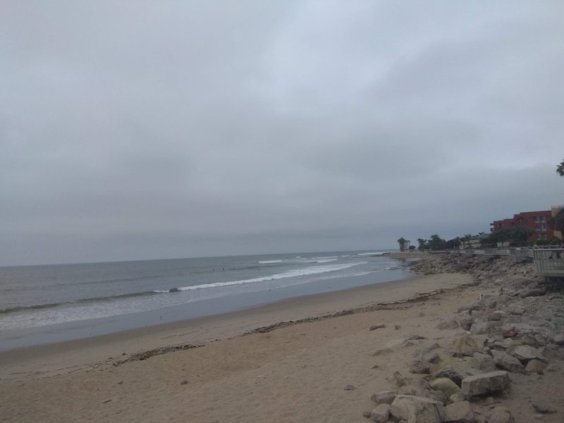 A view of the sandy and rocky shoreline at Emma Wood State Beach under an overcast sky.