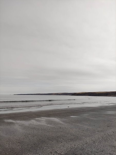 A wide view of the sandy beach and coastline at Eyvik under an overcast sky. — Eyvik (Húsavík), Húsavík, Iceland