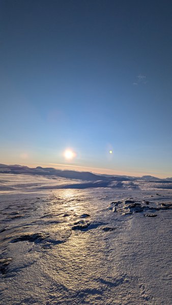 A vast snow-covered and icy landscape under a low sun, reflecting on the surface. — Dyratjornane (Eidfjord), Norway