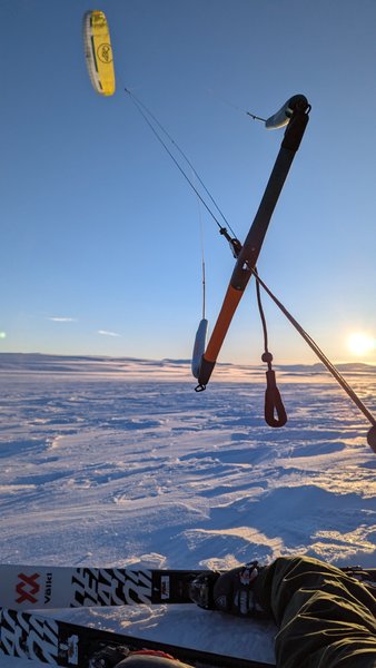 A snowkiter's perspective showing skis, control bar, and kite against a vast snowy landscape at sunset. — Dyratjornane (Eidfjord), Norway