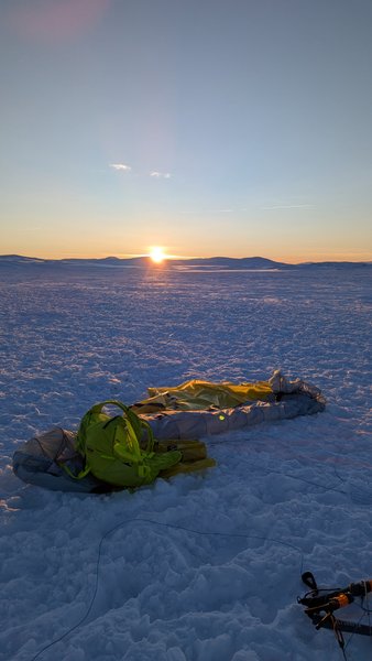 A snowkiting kite and backpack rest on a vast snow-covered plain at sunset. — Dyratjornane (Eidfjord), Norway