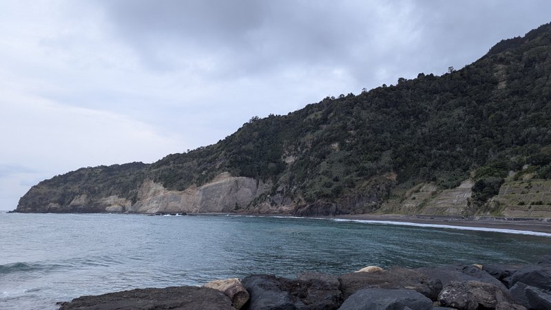 A view of the bay and sandy beach at Ribeira Quente surrounded by steep green cliffs. — Ribeira Quente (Costa da Povoação), Povoação, Portugal