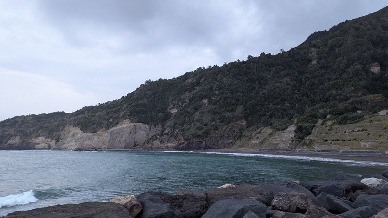 A view of the bay and beach at Ribeira Quente, backed by steep forested cliffs. — Ribeira Quente (Costa da Povoação), Povoação, Portugal