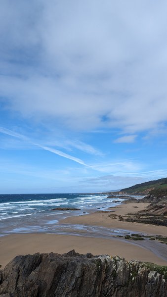 A wide view of the sandy beach and surf at Aviño.