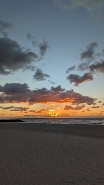 A wide sandy beach at sunset with waves breaking in the distance. — Praia do Areão, Praia de Mira, Portugal