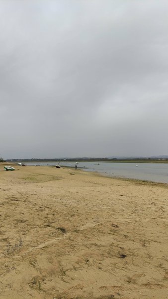A view of the sandy shore and calm water at Ilha de Faro under an overcast sky. — Ilha de Faro (Faro), Faro, Portugal