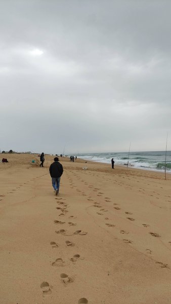 People walking along the sandy beach at Ilha de Faro under an overcast sky. — Ilha de Faro (Faro), Faro, Portugal