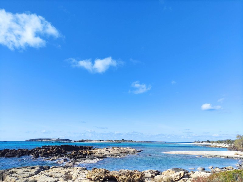 A wide landscape view of the clear turquoise water and rocky coastline at Elafonisi Beach. — Elafonisi-Strand (Kreta), Elafonisi Beach, Greece
