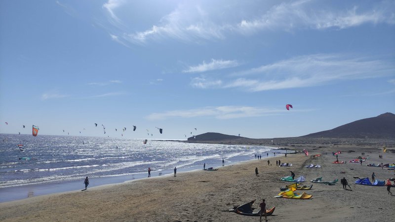 A wide view of the kitesurfing beach at El Médano with kites in the air and on the sand. — Muelle (El Médano), Granadilla de Abona, Canary Islands, Spain