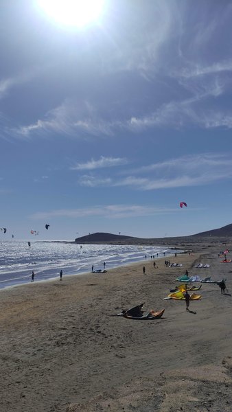 A wide view of the kitesurfing beach at El Médano with several kites in the air and on the sand. — Muelle (El Médano), Granadilla de Abona, Canary Islands, Spain