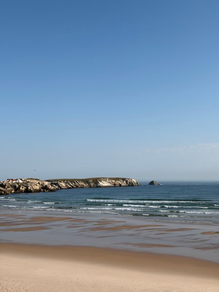 A clear view of the beach and rocky coastline at Lagide under a blue sky.