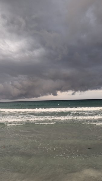 Small waves rolling onto La Cinta beach under heavy storm clouds. — La Cinta (San Teodoro), Santu Diadòru/San Teodoro, Sardinia, Italy