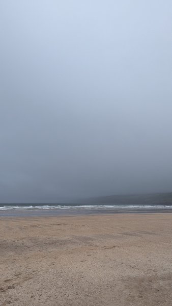 A wide view of a sandy beach and the ocean under a thick grey sky. — Inch Beach (Kerry), Ireland
