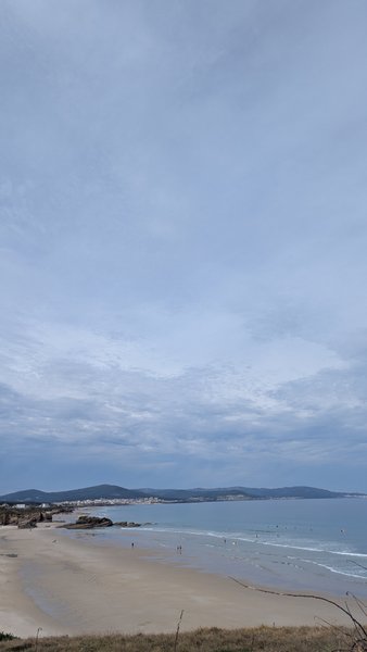 An expansive view of a sandy beach and bay with a distant town under a cloudy sky. — San Cosme (Foz), Suigrexa, Galicia, Spain